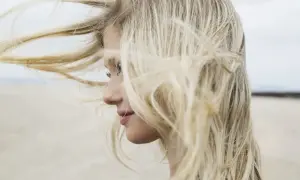 Profilo di una ragazza con lunghi capelli biondi mossi dal vento. Chissà se è il momento giusto quando tagliare i capelli luna.