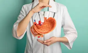 Modello anatomico di stomaco tenuto da mani, suggerisce digitopressione per reflusso gastrico.