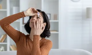 Donna applica collirio per alleviare la secchezza oculare, cercando rimedi naturali per il benessere dei suoi occhi.