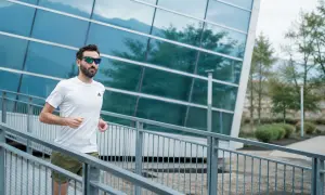 Uomo con occhiali da sole corre su una rampa metallica, godendosi i suoi 30 secondi di recupero tra le serie di allenamento.