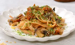 Pasta integrale con funghi e pomodori secchi, un'idea per le tue cucina macrobiotica ricette. Guarnita con semi di sesamo e prezzemolo.