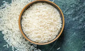 Chicchi di riso basmati in una ciotola e sparsi su una superficie scura. Scopri le proprietà del riso basmati.