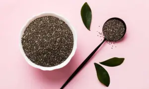 Semi di chia in una ciotola e un cucchiaio, con foglie verdi. Un aiuto naturale per la menopausa.