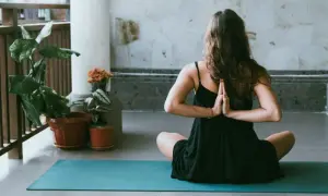 Donna in posizione yoga, mani giunte dietro la schiena, per alleviare i **secondo chakra bloccato sintomi**.