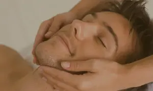 Un uomo rilassato riceve un massaggio al viso. Scopri il nostro corso di massaggio gratuito per imparare tecniche di benessere.