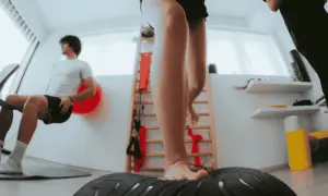 Allenamento per la riabilitazione crociato anteriore: un giovane si allena su una pedana instabile, mentre un altro esegue esercizi di potenziamento.