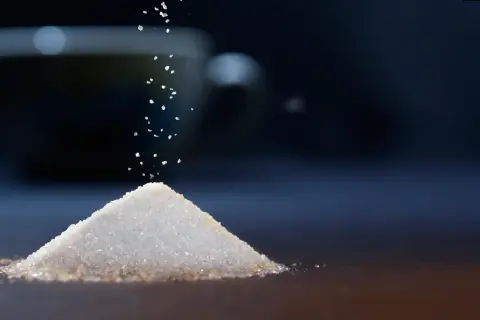 Granello di zucchero cade su una piramide. Il sucralosio, un dolcificante, è un'alternativa per chi soffre di diabete.