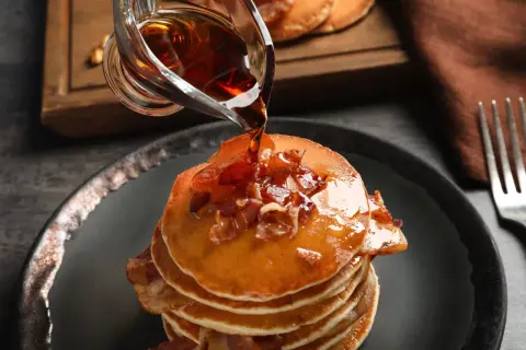 Pancakes con sciroppo d'acero e bacon. Meglio sciroppo d'acero o agave? La scelta è tua per questa delizia.