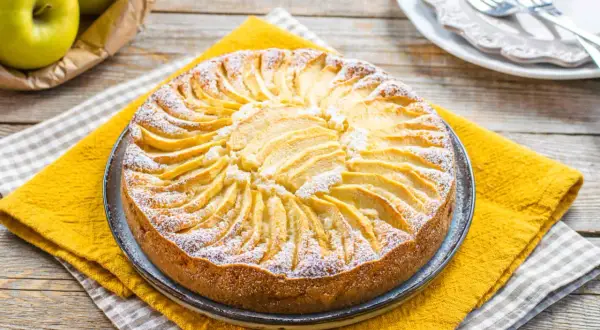 Torta di mele decorata con fettine disposte a raggiera, spolverata di zucchero a velo. Un'idea per torte senza zucchero.