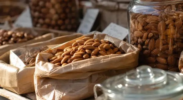 Sacchetti di carta pieni di mandorle, invitano a chiedersi quante mandorle al giorno siano ideali per uno spuntino sano.