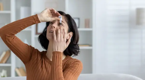 Donna applica collirio per alleviare la secchezza oculare, cercando rimedi naturali per il benessere dei suoi occhi.
