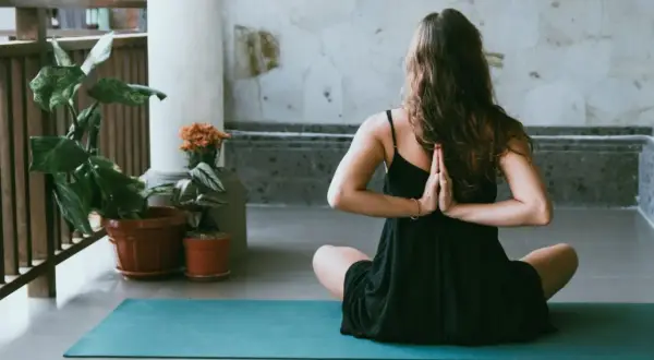 Donna in posizione yoga, mani giunte dietro la schiena, per alleviare i **secondo chakra bloccato sintomi**.