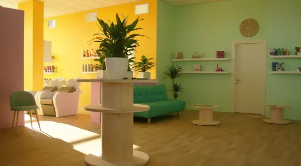 Salone moderno con pareti giallo e verde menta. Il colore azzurro significato di tranquillità è evocato dal divanetto, mentre le piante portano vitalità.