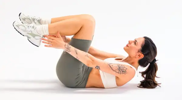 Donna con tatuaggi fa crunch, frustrata per l'aumento di peso nonostante dieta e palestra.