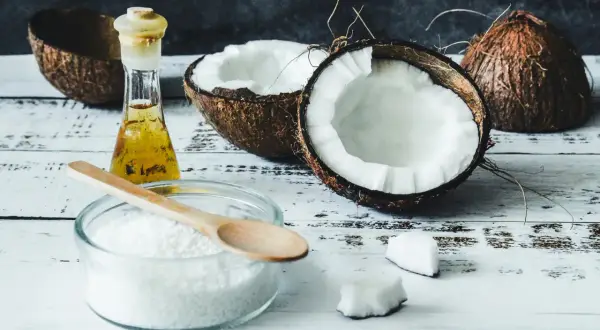 Scopri come usare olio di cocco in cucina: cocco fresco, olio dorato e farina bianca pronti per creare piatti esotici.