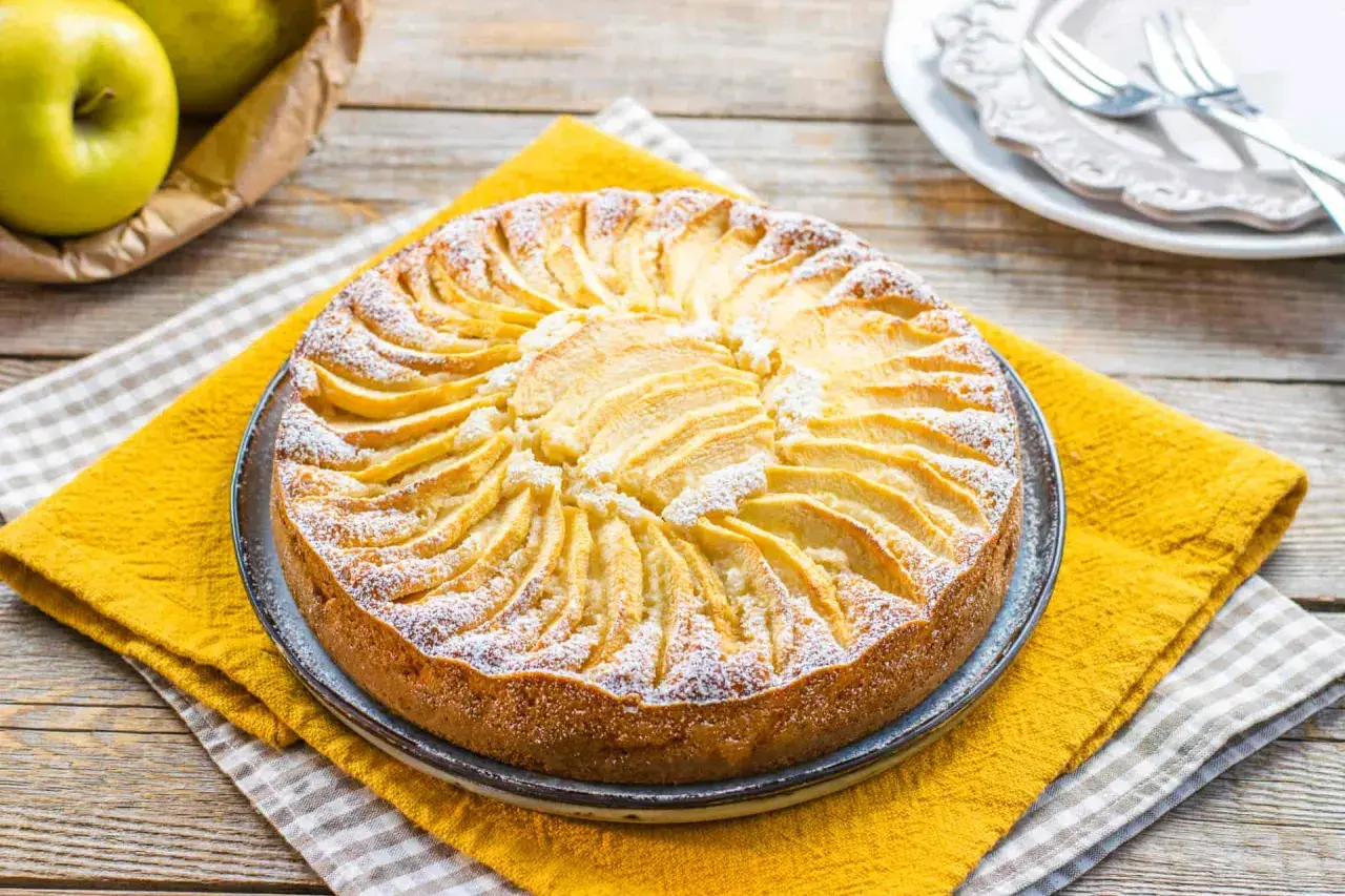 Torta di mele decorata con fettine disposte a raggiera, spolverata di zucchero a velo. Un'idea per torte senza zucchero.