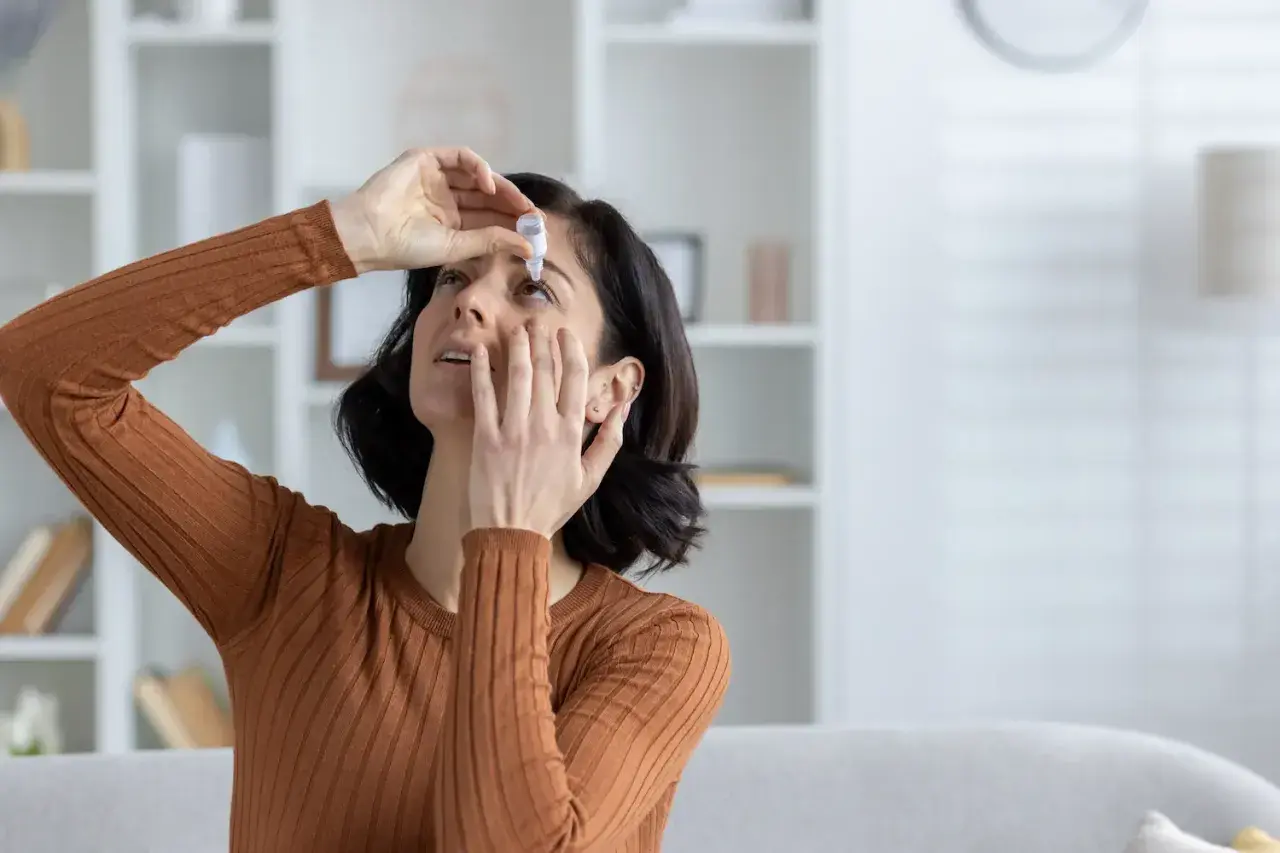 Donna applica collirio per alleviare la secchezza oculare, cercando rimedi naturali per il benessere dei suoi occhi.