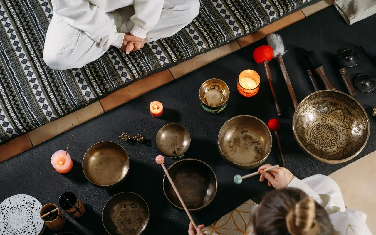 Operatore olistico stipendio: ciotole tibetane, candele e bacchette per un massaggio sonoro rilassante.