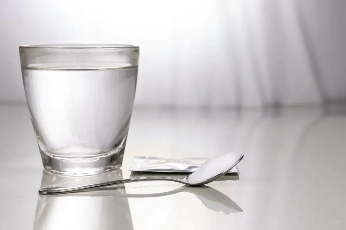 Un bicchiere d'acqua e un cucchiaino con sale, un rimedio semplice per come alzare la pressione bassa.