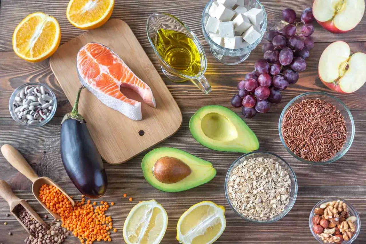 Ingredienti per una dieta sana: salmone, avocado, arance, uva, mele, melanzane, legumi, cereali, frutta secca, olio d'oliva. Ottimi rimedi naturali colesterolo.