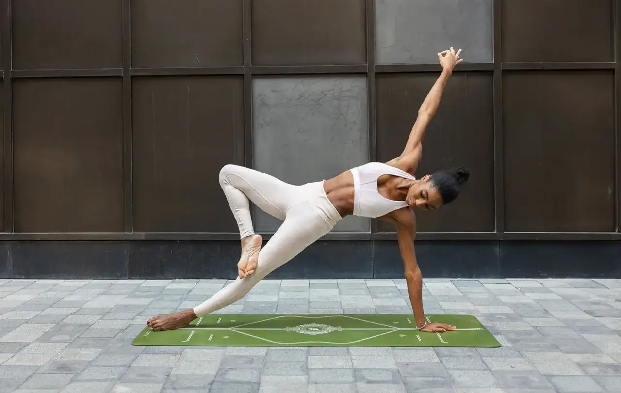 Donna in posa yoga su tappetino verde, un esempio di 10 esercizi per migliorare l'equilibrio.