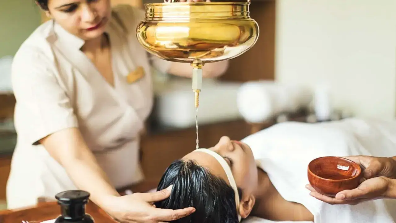 Un massaggio ayurvedico con olio caldo sulla fronte per rilassare mente e corpo, uno dei tanti benefici di questa pratica millenaria.