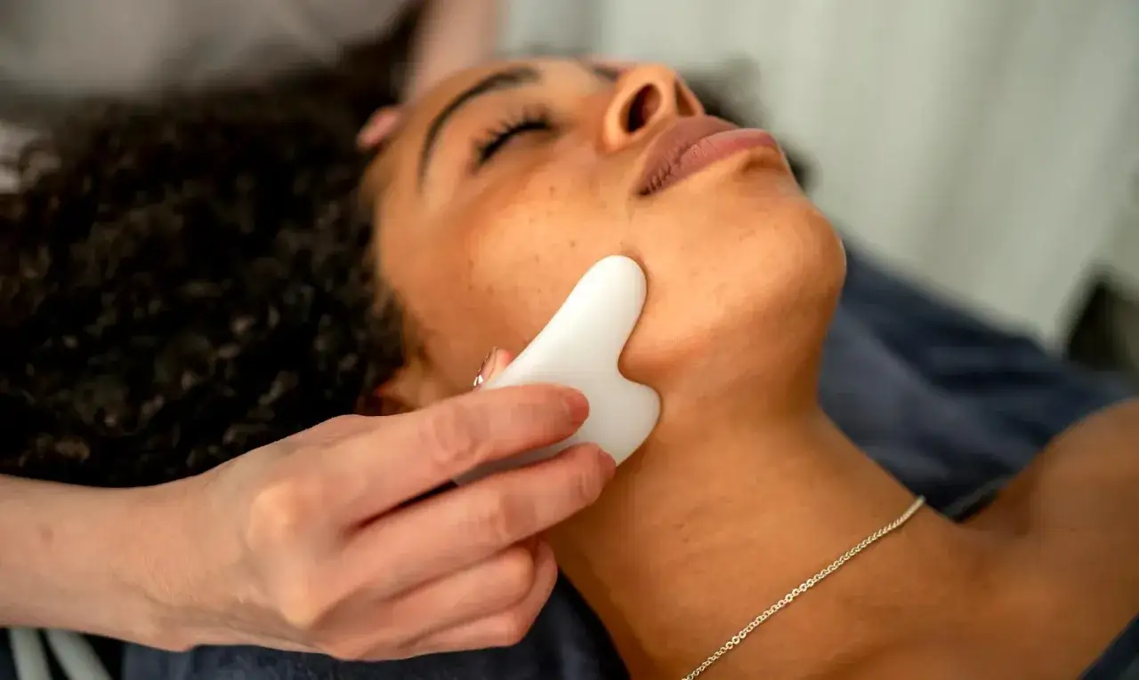 Massaggio viso con pietra gua sha. Attenzione alle gua sha controindicazioni per evitare irritazioni.