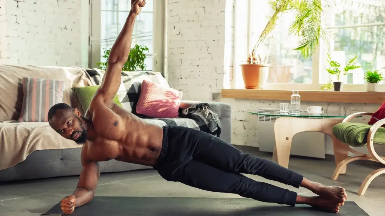 Uomo in posizione di plank laterale, un ottimo esercizio per i migliori esercizi addominali. Allenamento a casa con addominali scolpiti.