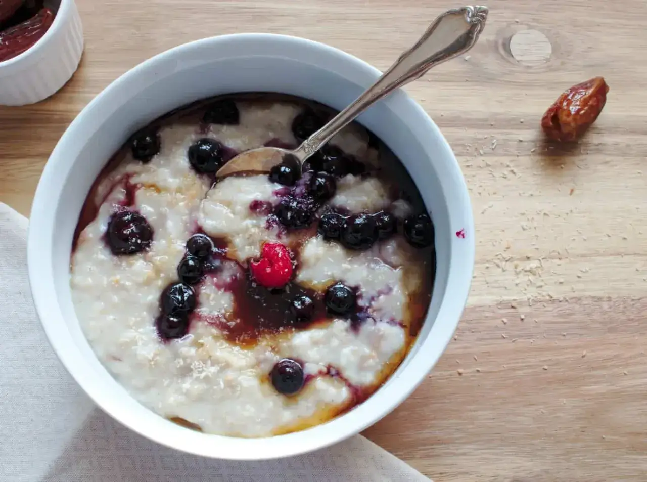 Porridge con mirtilli e lampone, guarnito con sciroppo. Attenzione: il porridge senza cottura fa male!