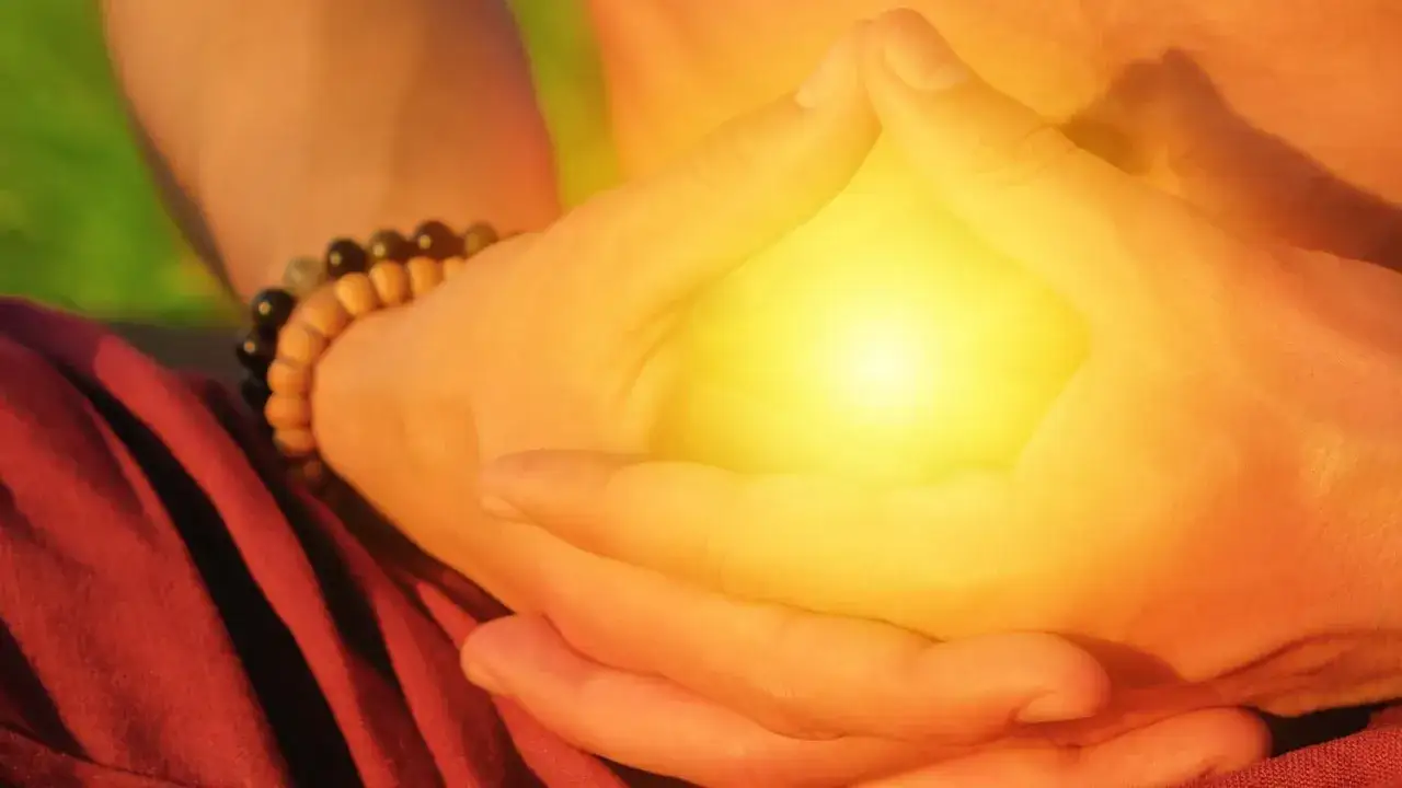 Mani giunte in meditazione, un bagliore giallo intenso tra le dita. Forse un modo per sciogliere i terzo chakra bloccato sintomi.