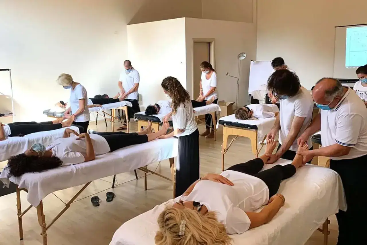 Persone sdraiate su lettini da massaggio, mentre altre praticano tecniche. Un'opportunit&agrave; per un corso di massaggio gratuito.