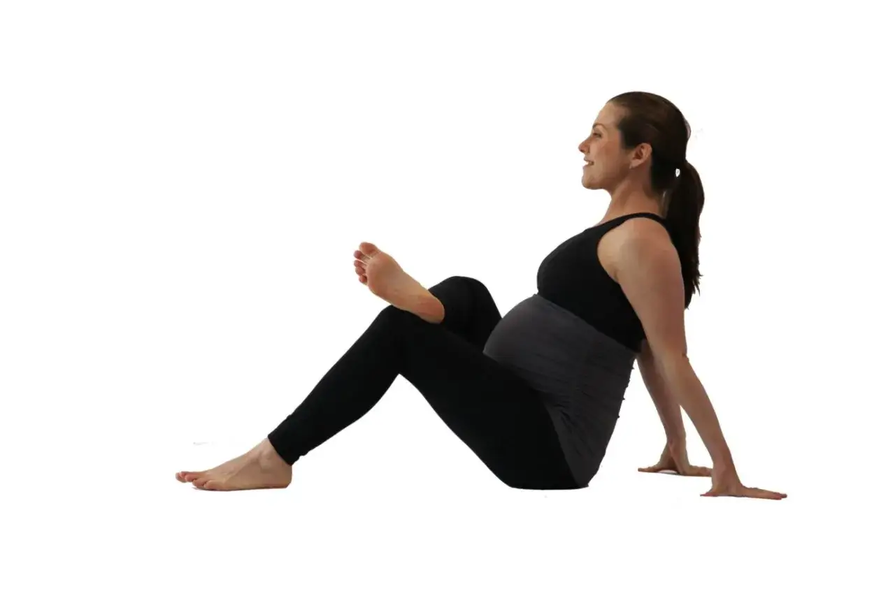 Donna incinta in posizione yoga, utile per alleviare il mal di schiena in gravidanza nel secondo trimestre.