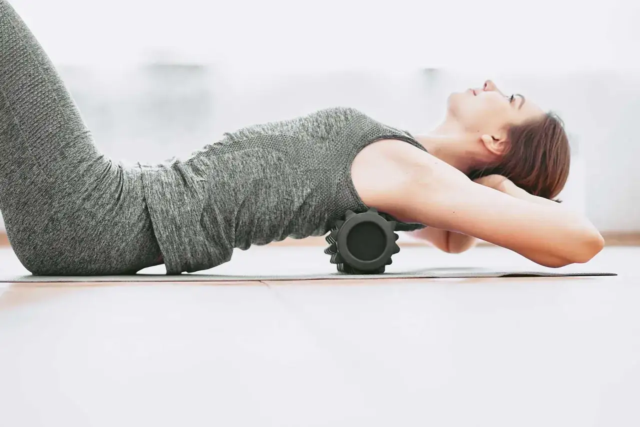 Donna si rilassa con un foam roller per alleviare la contrattura schiena alta.