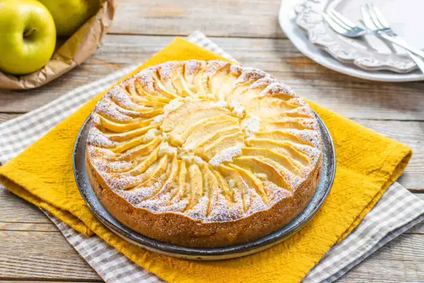 Torta di mele decorata con fettine disposte a raggiera, spolverata di zucchero a velo. Un'idea per torte senza zucchero.