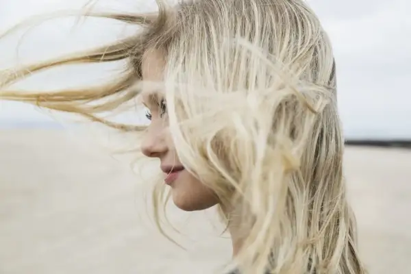 Profilo di una ragazza con lunghi capelli biondi mossi dal vento. Chissà se è il momento giusto quando tagliare i capelli luna.