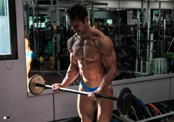 Atleta muscoloso esegue esercizi tricipiti macchinari con bilanciere in palestra.