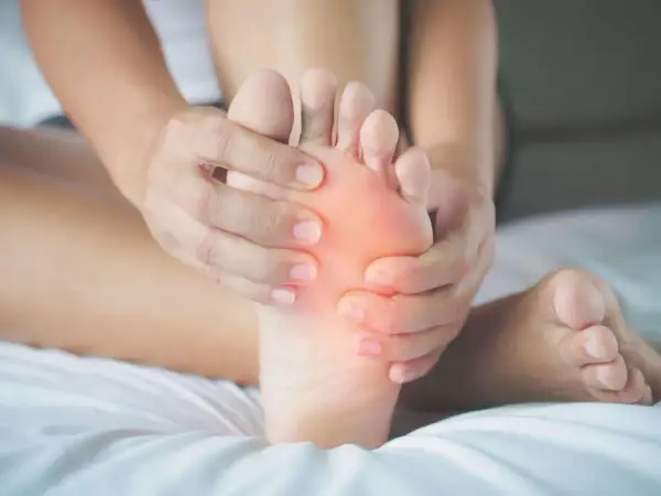 Mani che massaggiano un piede, evidenziando il dolore sotto le dita. Si cercano rimedi naturali per alleviare il fastidio.