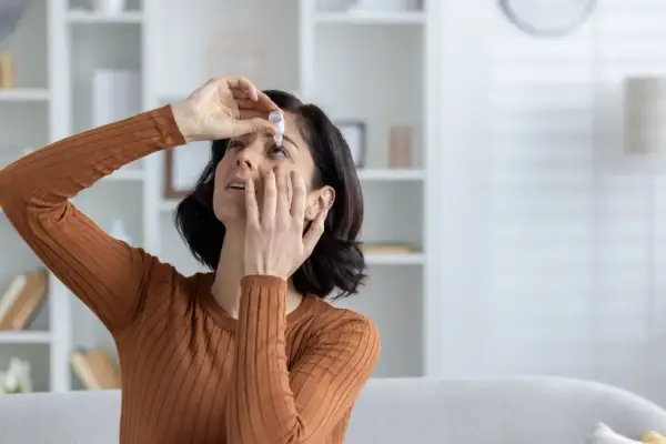 Donna applica collirio per alleviare la secchezza oculare, cercando rimedi naturali per il benessere dei suoi occhi.