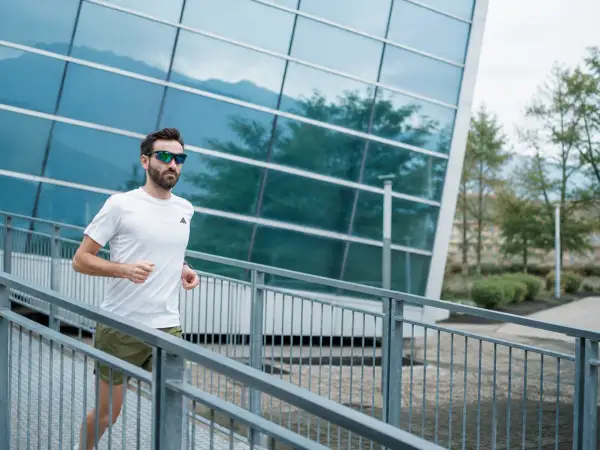 Uomo con occhiali da sole corre su una rampa metallica, godendosi i suoi 30 secondi di recupero tra le serie di allenamento.