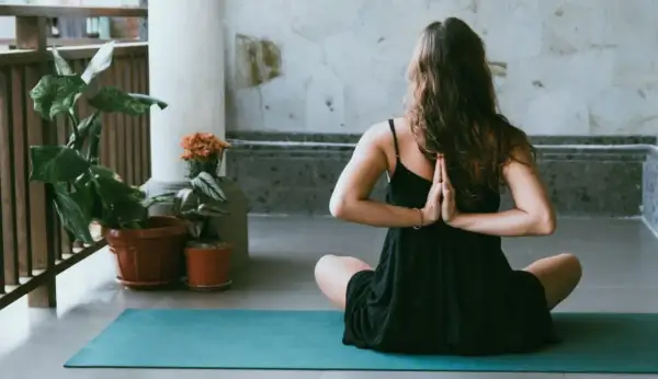 Donna in posizione yoga, mani giunte dietro la schiena, per alleviare i **secondo chakra bloccato sintomi**.