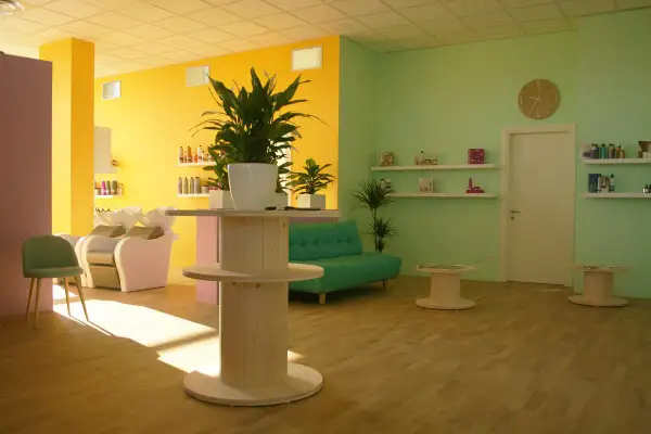 Salone moderno con pareti giallo e verde menta. Il colore azzurro significato di tranquillità è evocato dal divanetto, mentre le piante portano vitalità.