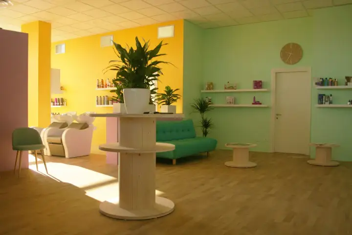 Salone moderno con pareti giallo e verde menta. Il colore azzurro significato di tranquillità è evocato dal divanetto, mentre le piante portano vitalità.